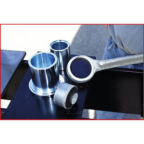 Werkzeug und Metallteile auf schwarzem Untergrund. Ein Mann hält einen Schraubenschlüssel.